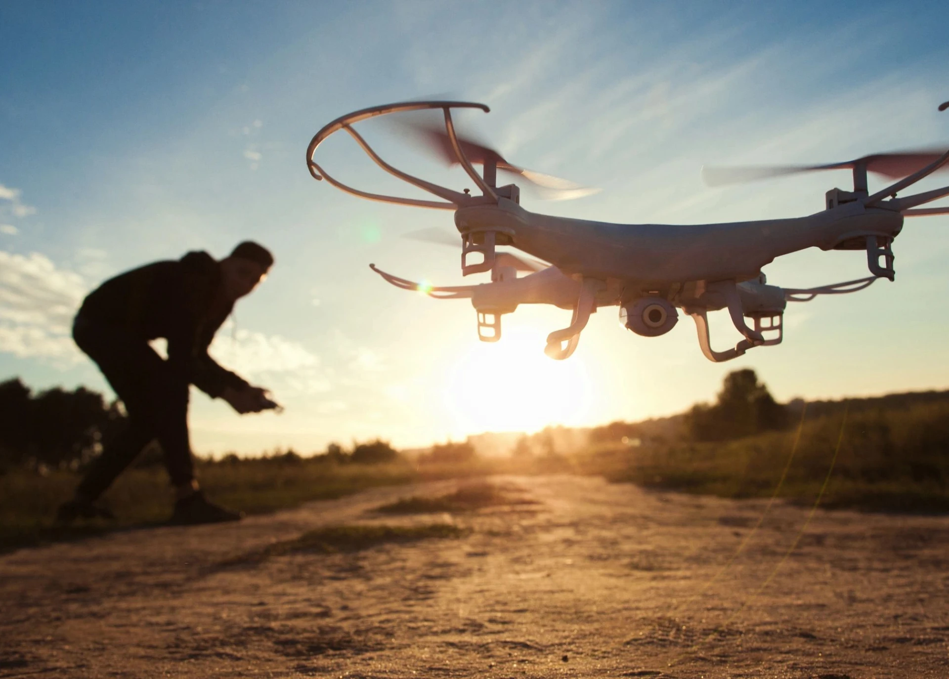 Drone flying at sunset with person nearby
